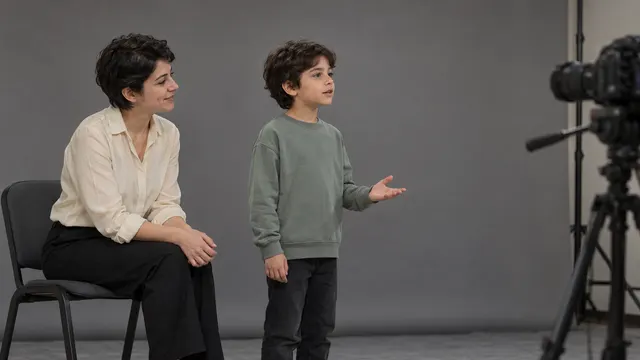 Pencere ışığında doğal başvuru fotoğrafı çekilen çocuğun yanında duran ve hazırlığa destek olan velisi