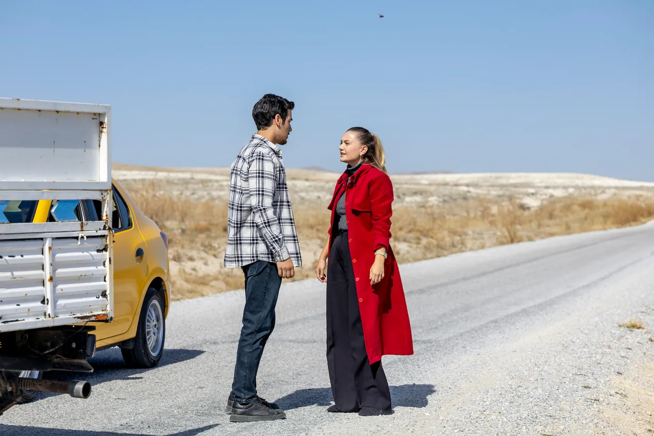 Erkek ve kırmızı montlu kadın yol kenarında konuşuyor.